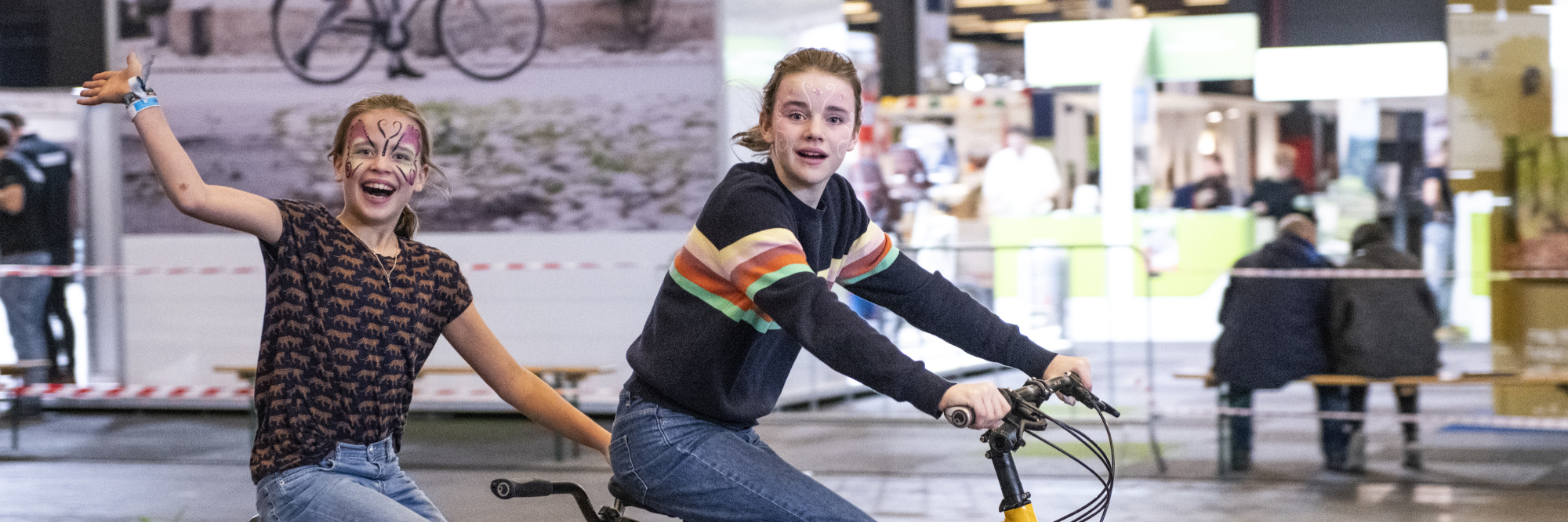 Terugblik op 2020: zwaaiende meisjes op een tandem tijdens de recordeditie 2020 van de gecombineerde Fiets en Wandelbeurs, E-bike Challenge en Mount Expo.  