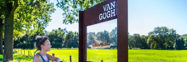 Vrouw bij een bord langs de Van Gogh Drenthe Fietsroutes, de Fietsroute van het Jaar 2024